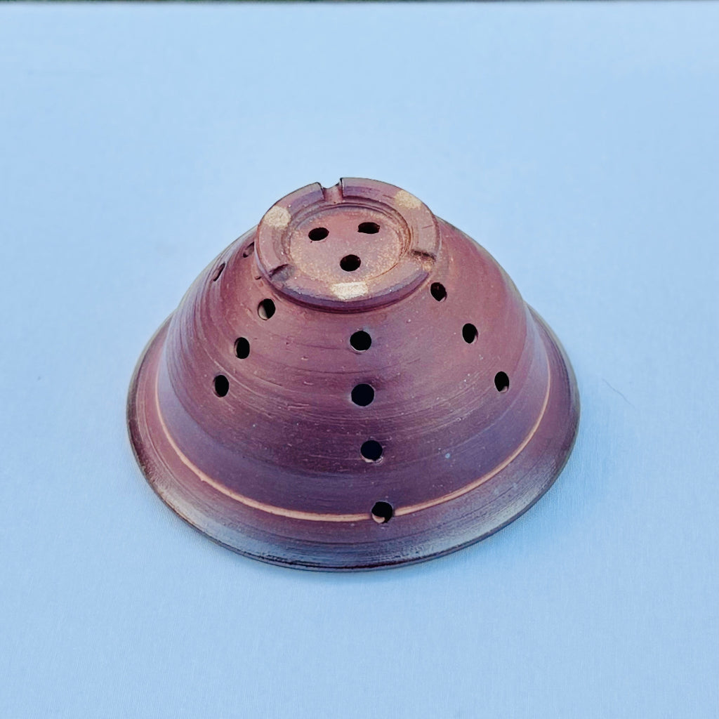 Wood-fired pottery bowl showing natural clay body and kiln effects and sturdy foot with three drain holes