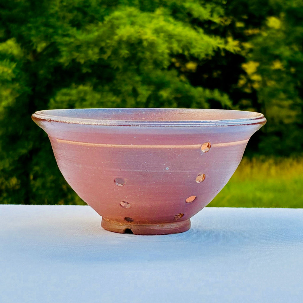 Wood fired ceramic berry bowl with natural brown tones and spiral interior design and drain holes for washing fresh berries
