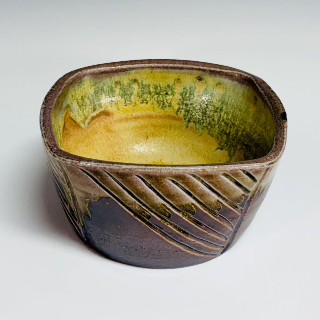 Square ceramic planter showing yellow-green interior glaze and drainage hole