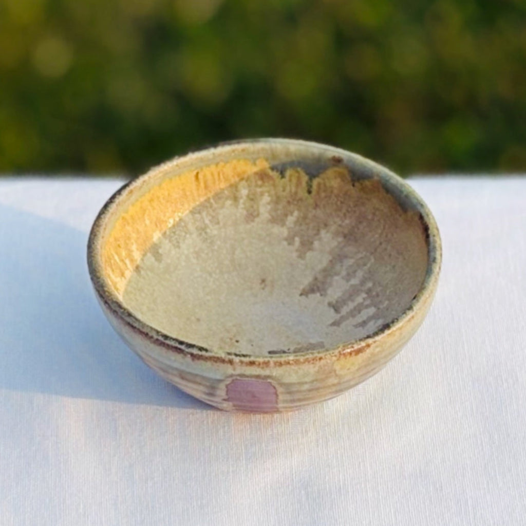 Interior view of pottery ring dish with a soft yellow interior and green soft brown green drips