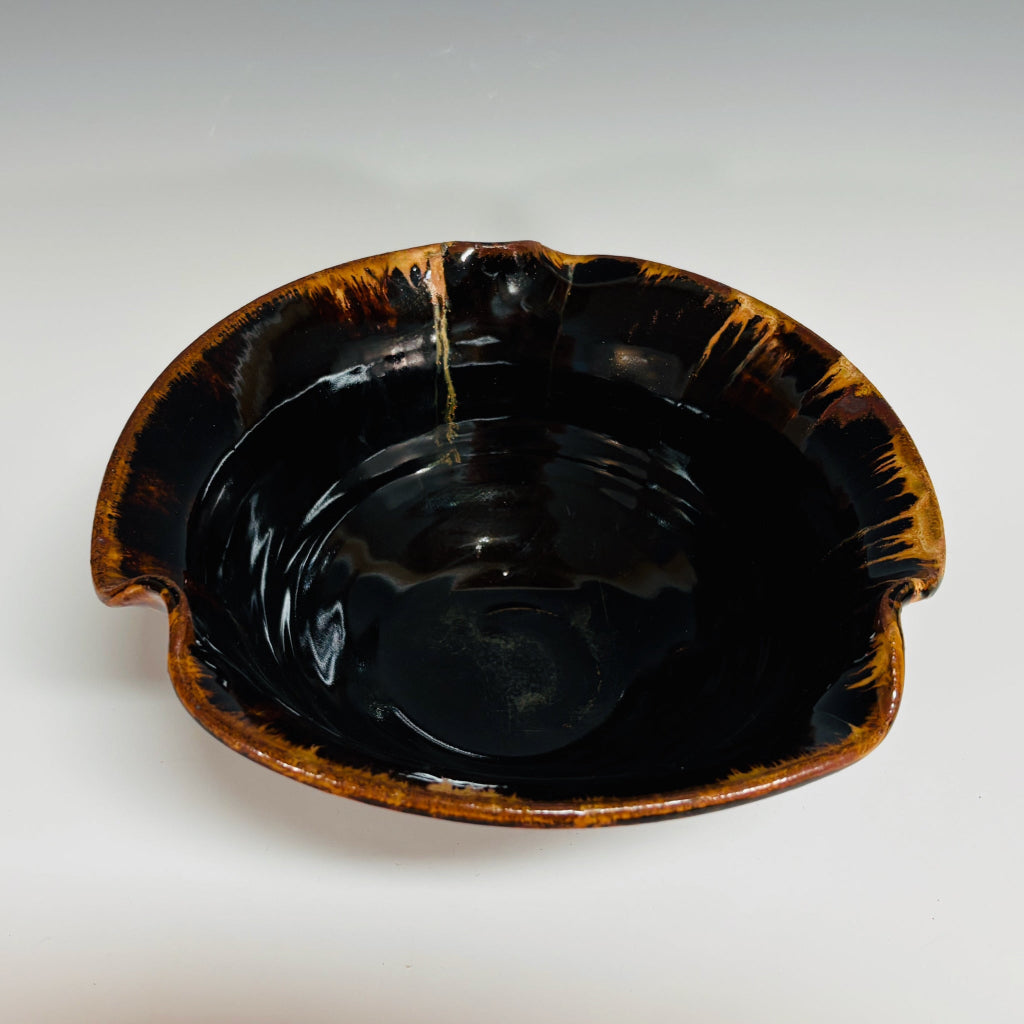 dark brown/black pottery bowl with high shine glaze and a amber rims