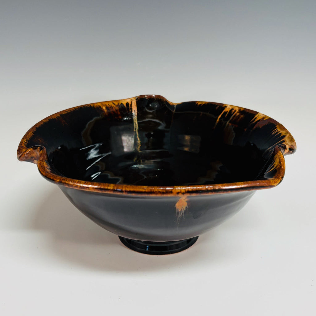 Shiny dark brown pottery bowl with high shine glaze interior and a amber rims and drips