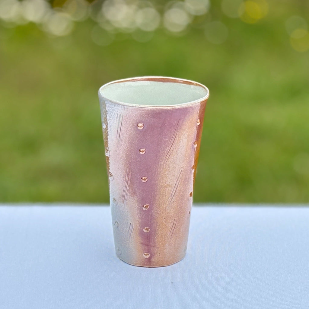Lightweight porcelain tumbler with a white interior and dots and incised lines on the exterior