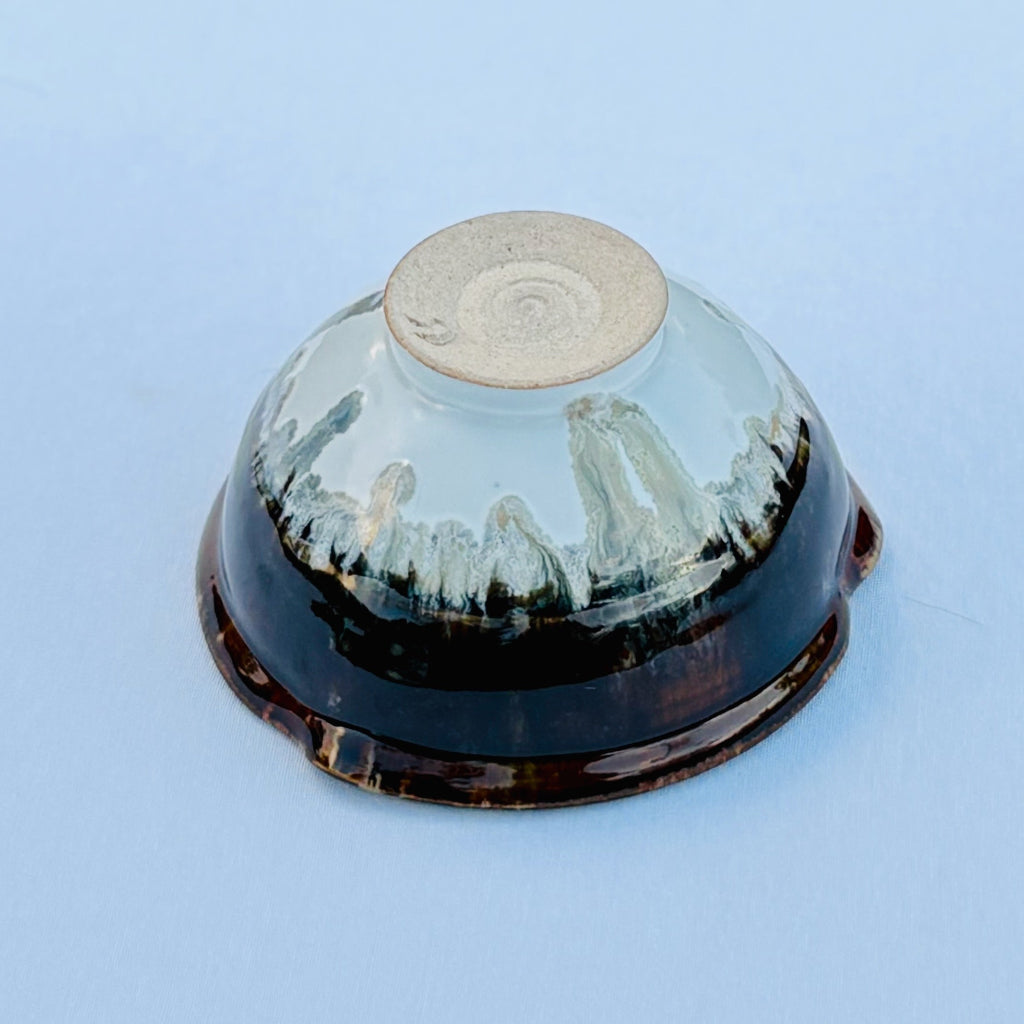 Handcrafted ceramic bowl showing foot ring with artists marking and white glaze, waterfall marks, and a rich brown glaze top